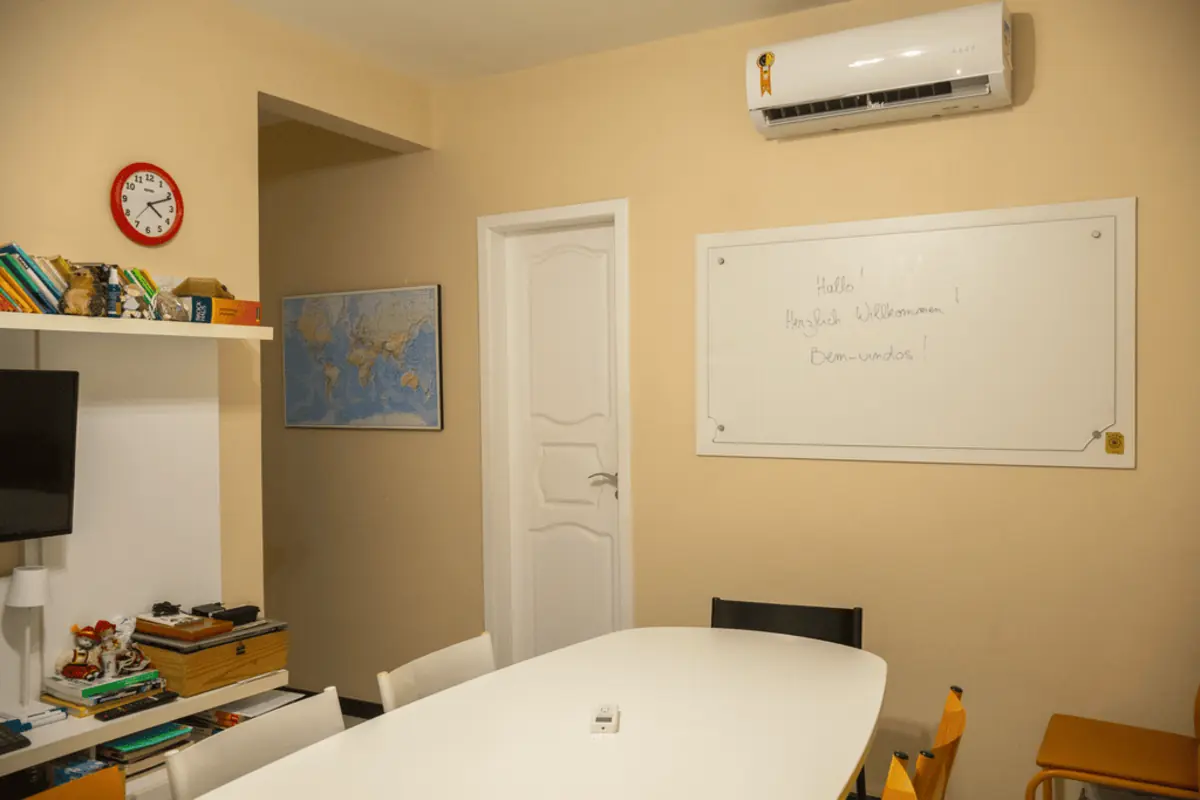 Sala de aula da KONTAKT, com mapa-múndi, estante de livros e quadro branco de boas-vindas